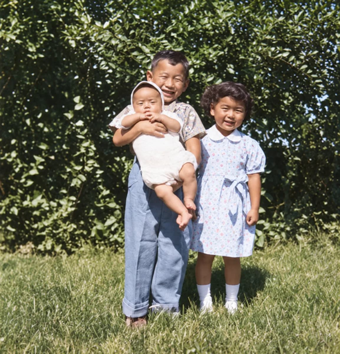 After: black-and-white snapshot of a boy holding a baby next to a young girl on a lawn