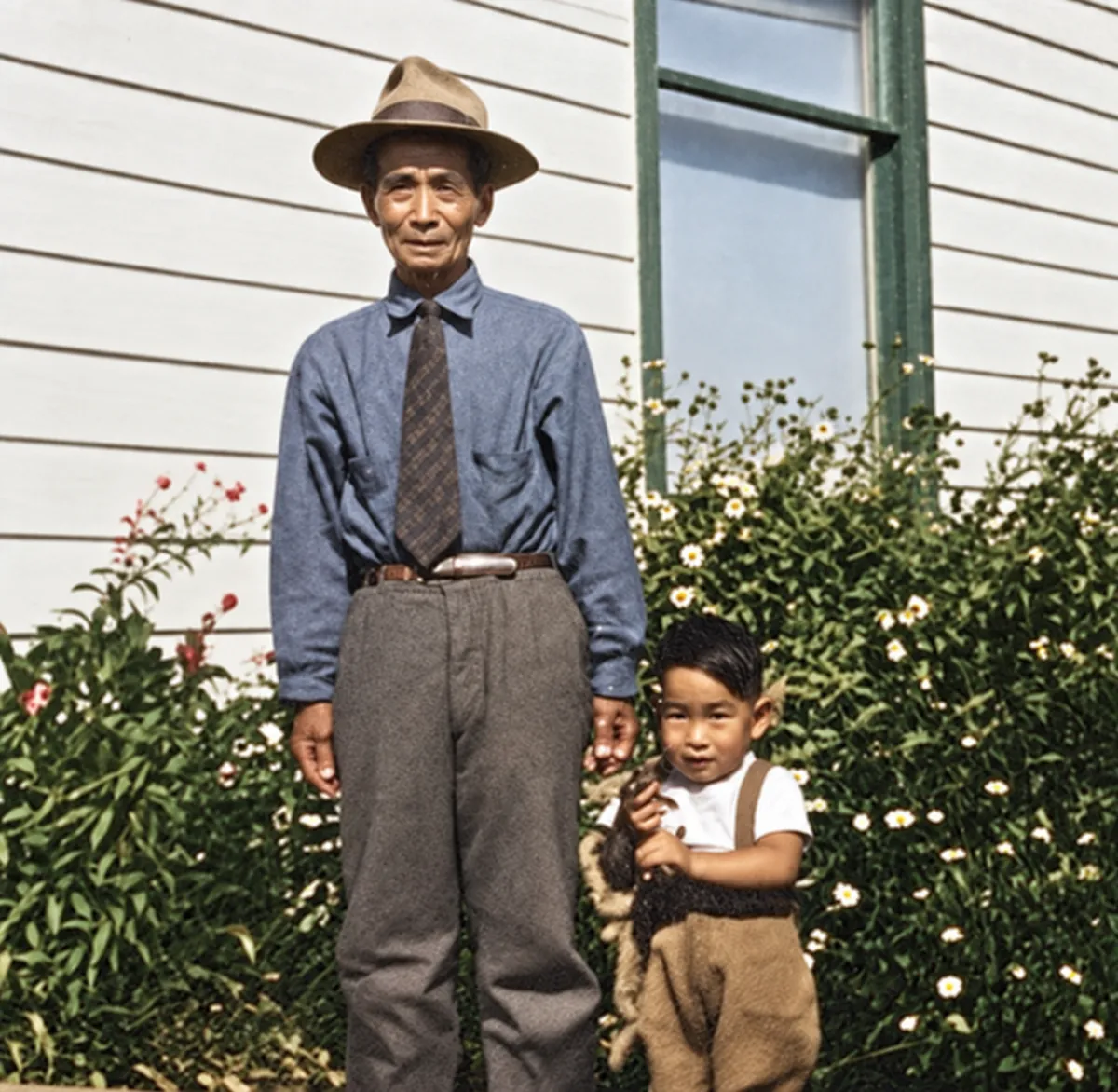 After: water-stained snapshot of a man in a hat and a young boy beside a house