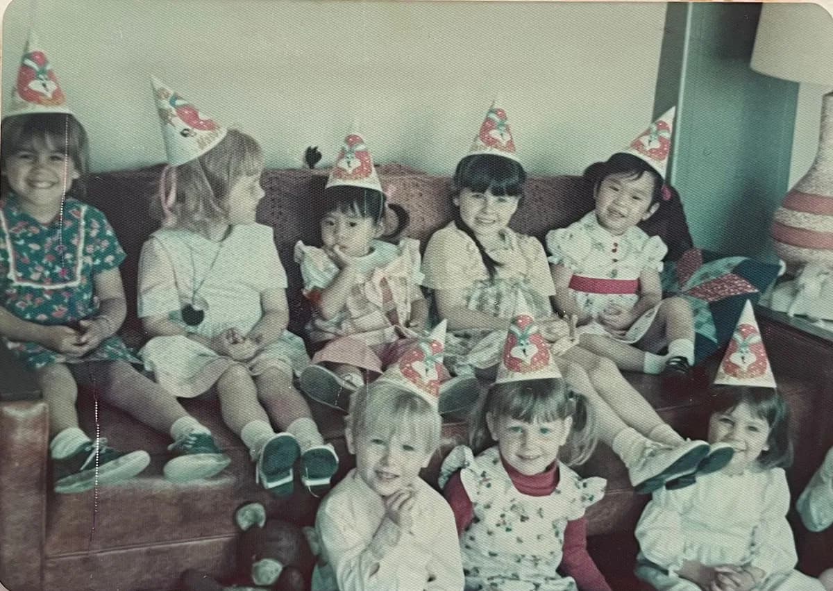 Before: faded color snapshot of children in party hats sitting on a couch